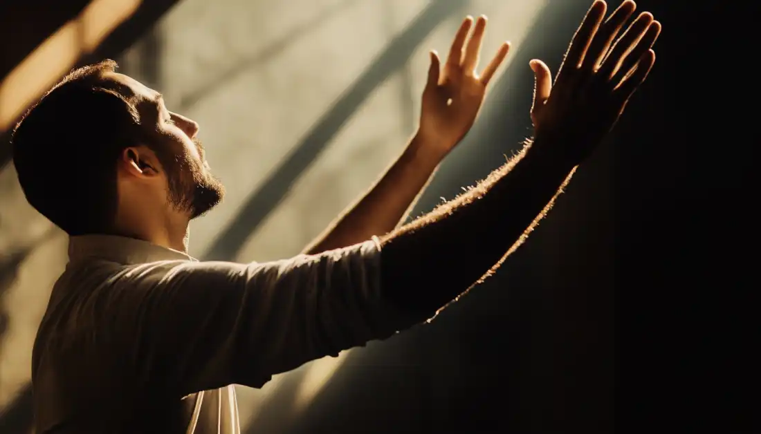 A man kneeling in prayer and lifting his hands in worship, finding strength through God’s presence.