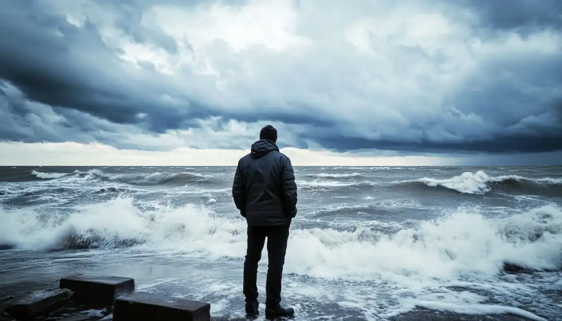 A man standing at the edge of a stormy sea, symbolizing the struggle of self-doubt and the choice to trust God