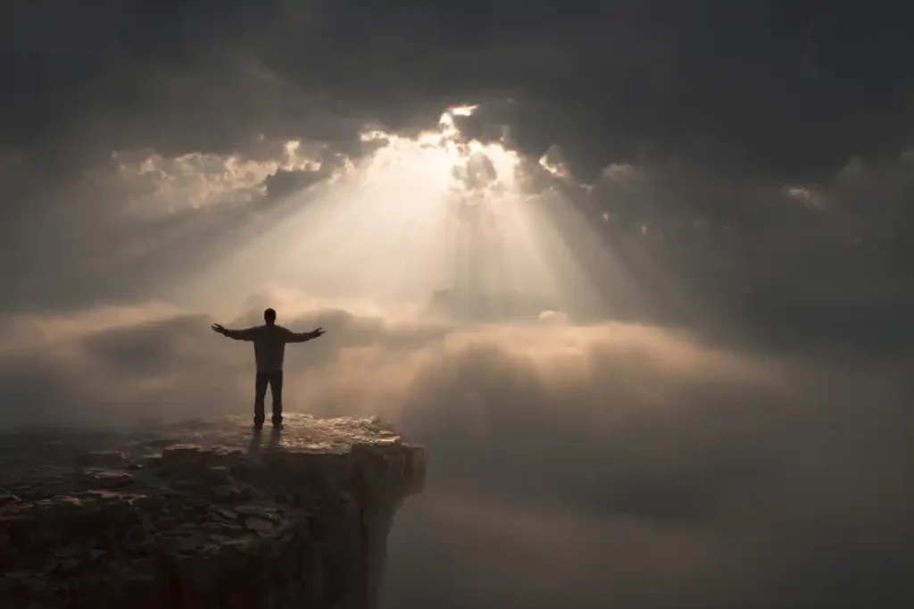 A man holding a Bible on a cliffside, standing strong in God’s promises.