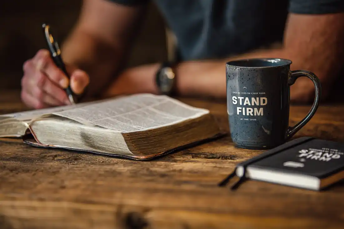A man journaling with a Bible open, preparing to stand firm in faith.